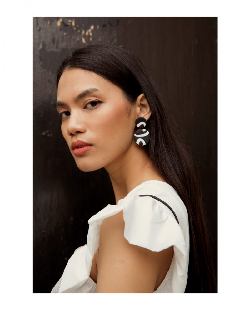 Model wearing black and white earrings