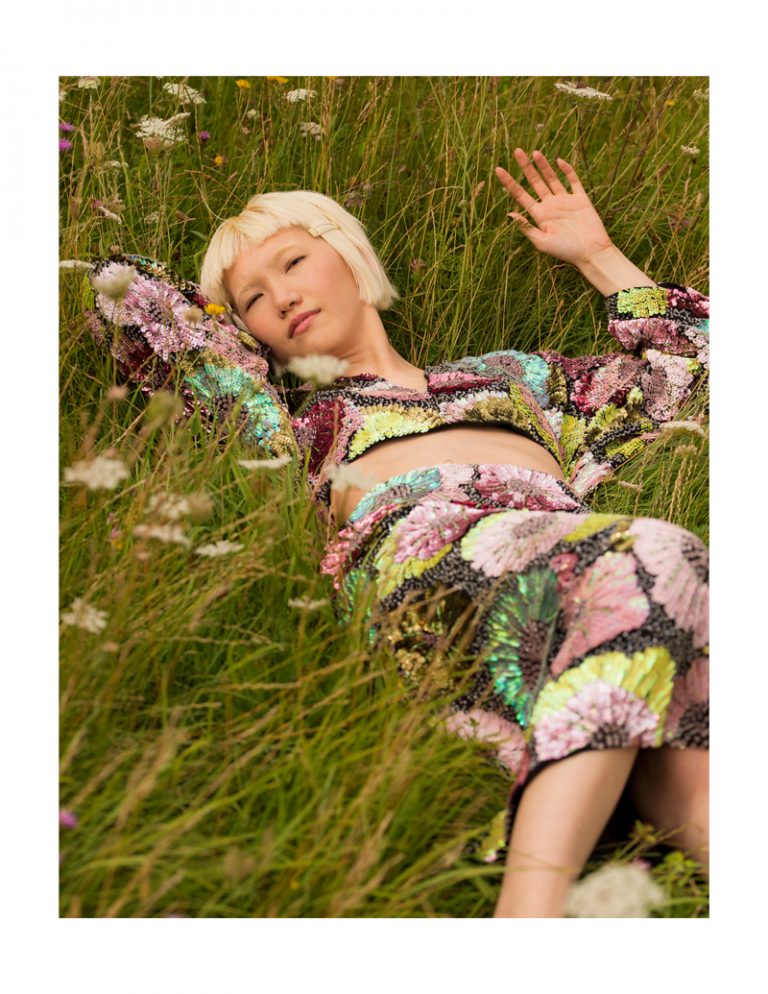 Model laying in the grass with a flower dress