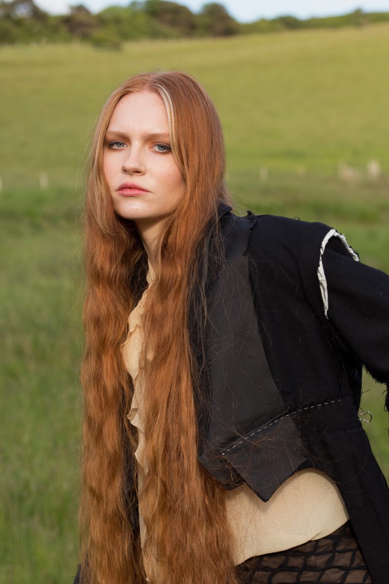 Fashion Editorial - A woman with red hair and long flowing locks wearing a black and yellow outfit.