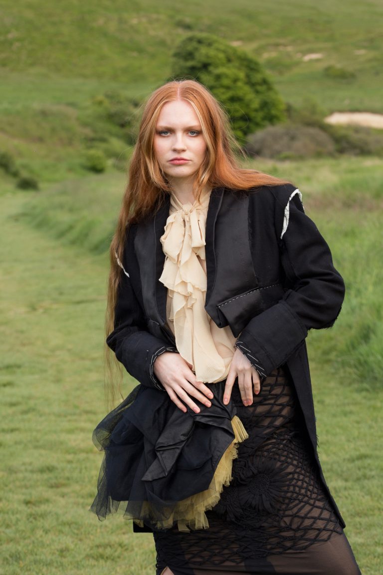 Fashion Editorial - A woman with red hair and long flowing locks wearing a black and yellow outfit.