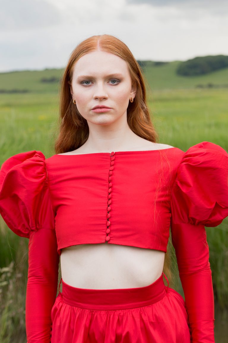 Fashion Editorial - A woman with red hair and long flowing locks wearing a red dress.