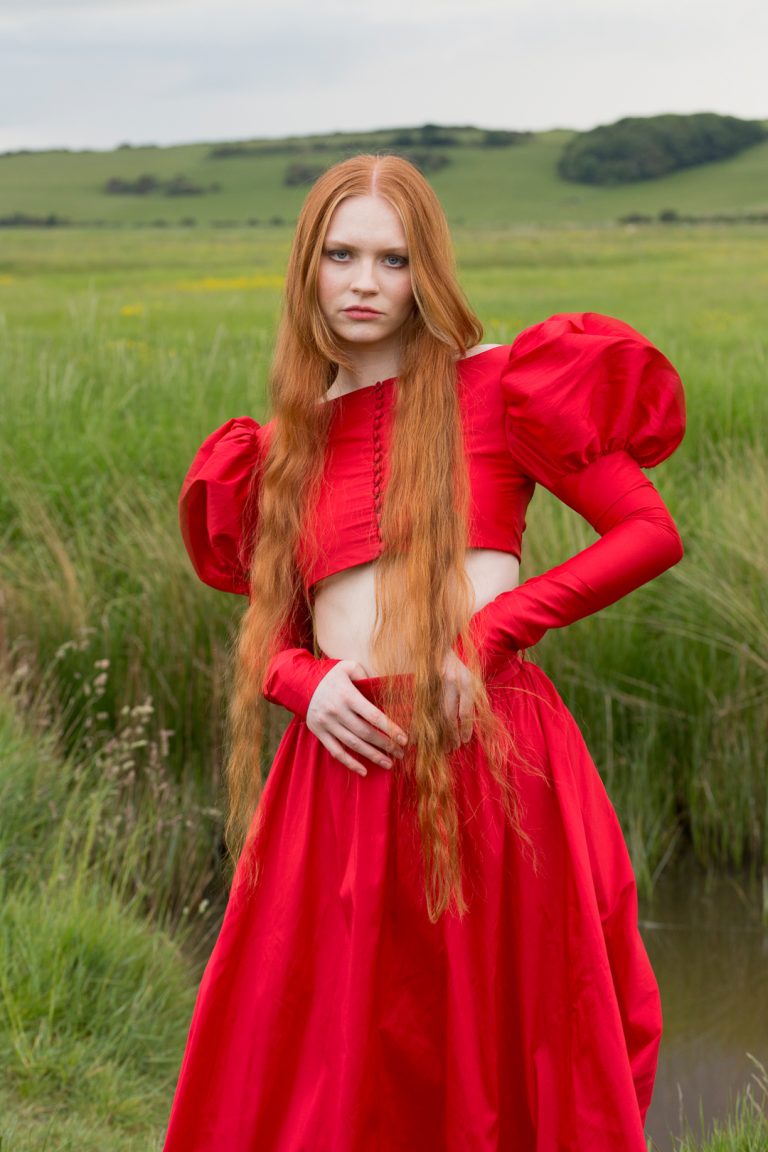 Fashion Editorial - A woman with red hair and long flowing locks wearing a red dress.