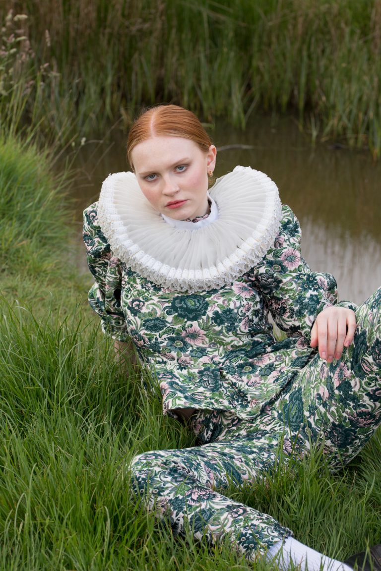 Fashion Editorial - A woman with red hair in a pony tail wearing a green flower two piece outfit.