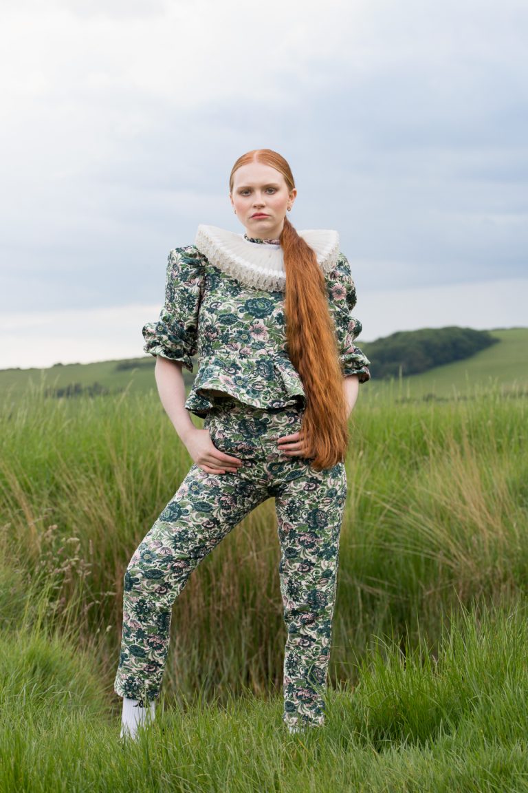 Fashion Editorial - A woman with red hair in a pony tail wearing a green flower two piece outfit.