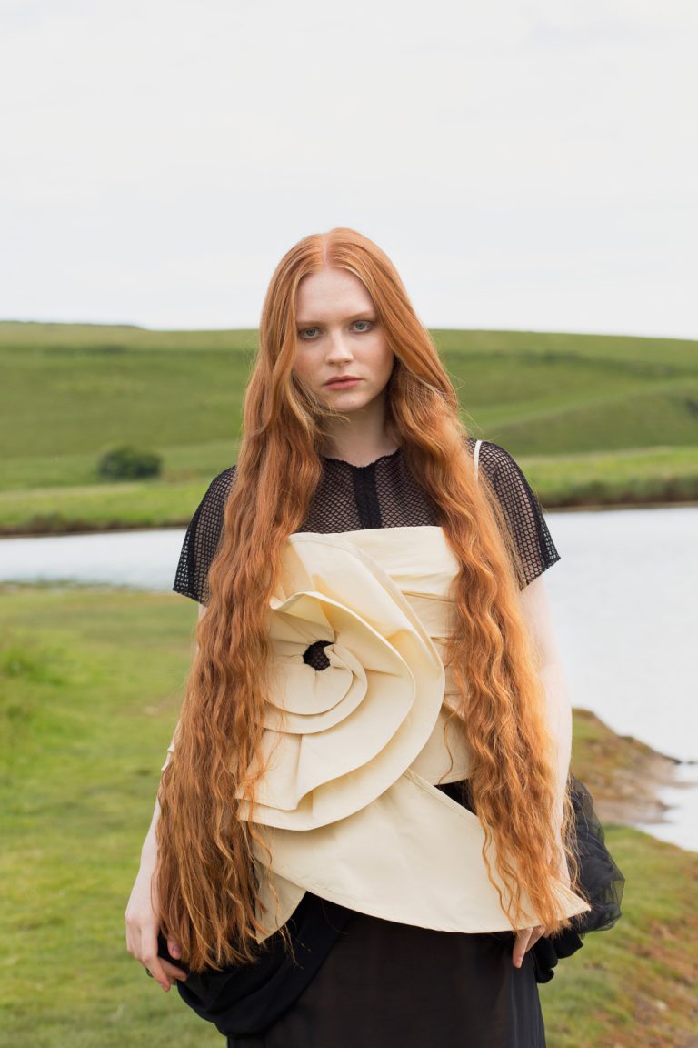 Fashion Editorial - A woman with red hair and long flowing locks wearing a black and yellow dress.