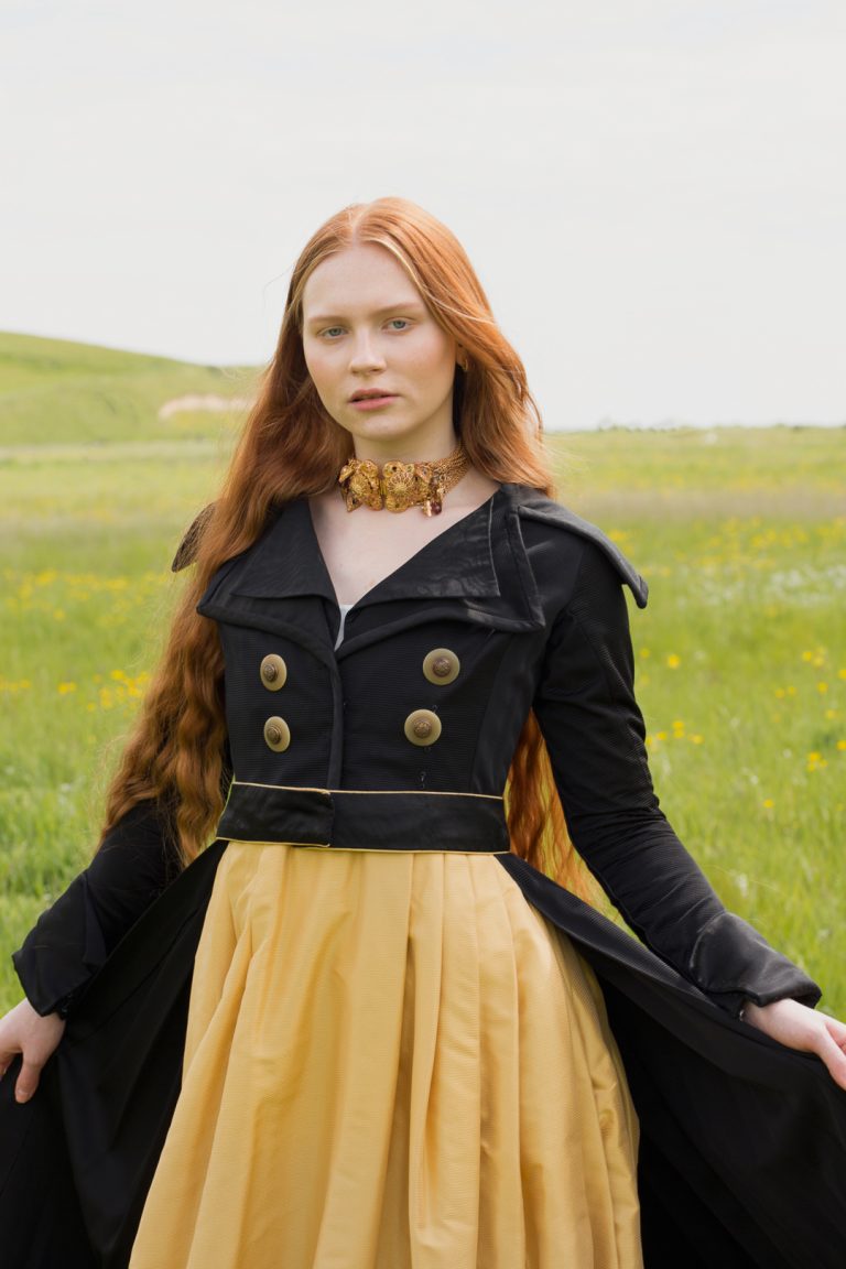 Fashion Editorial - A woman with red hair and long flowing locks wearing a black and yellow dress.