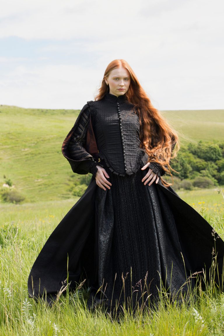 Fashion Editorial - A woman with red hair and long flowing locks wearing a black dress.