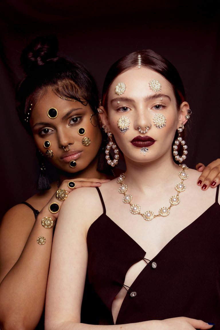 Two models wearing elegant gold and black jewellery, showcasing a sophisticated and stylish look. Baroque beauty fashion shoot.