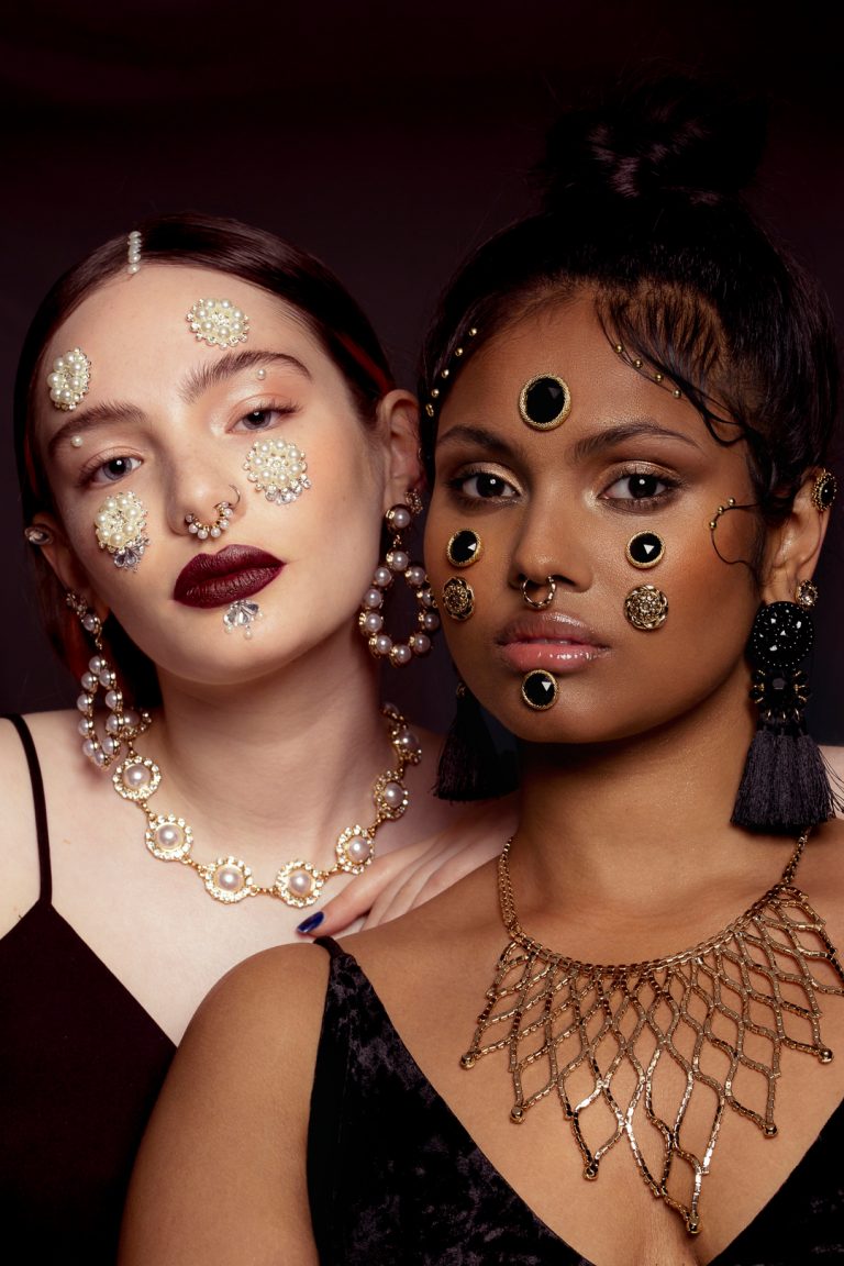 Two models wearing elegant gold and black jewellery, showcasing a sophisticated and stylish look. Baroque beauty fashion shoot.