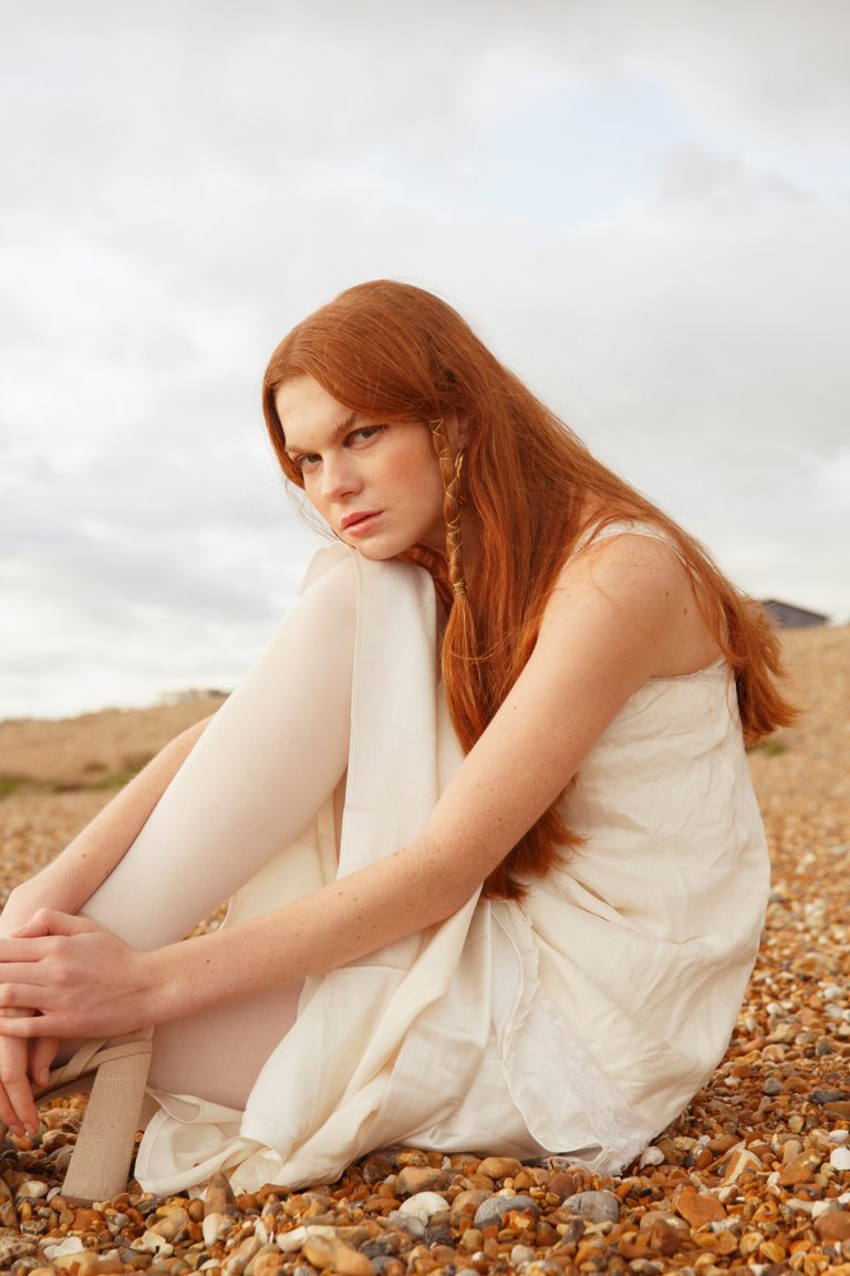 Beautiful model wearing white dress in a winter fashion shoot by Brighton seafront.