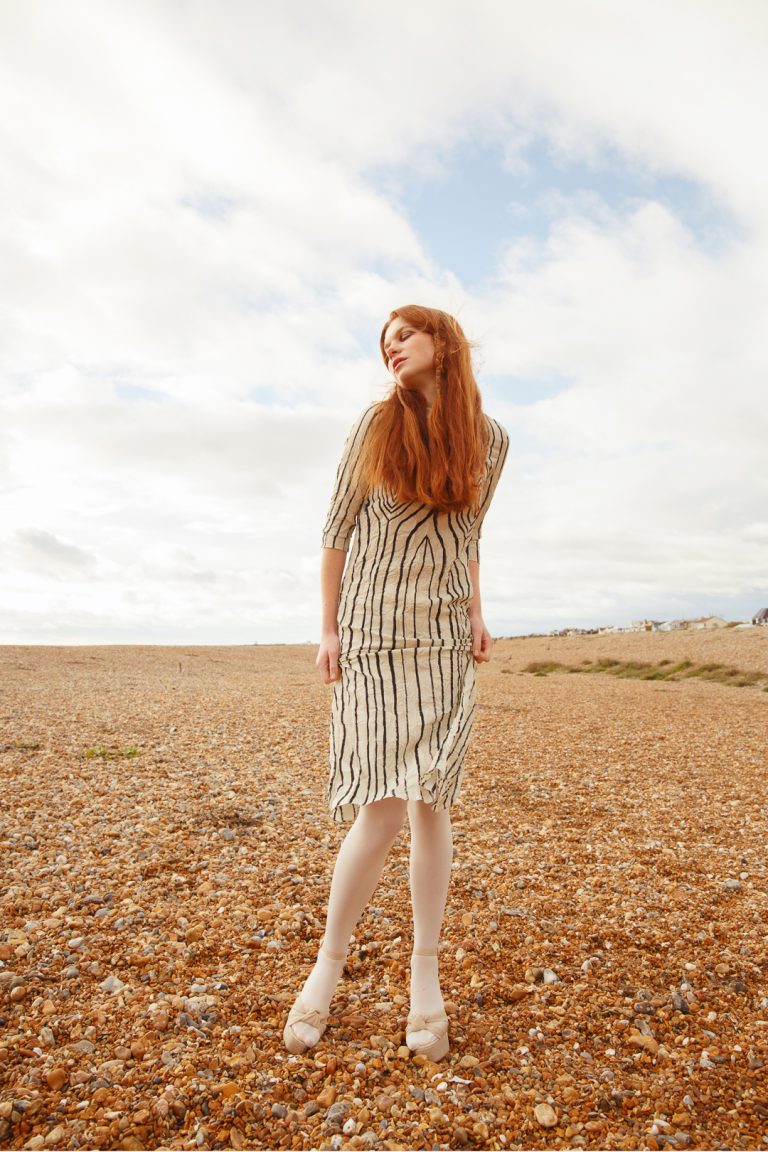 Beautiful model wearing white & black stripe dress in a winter fashion shoot by Brighton seafront.