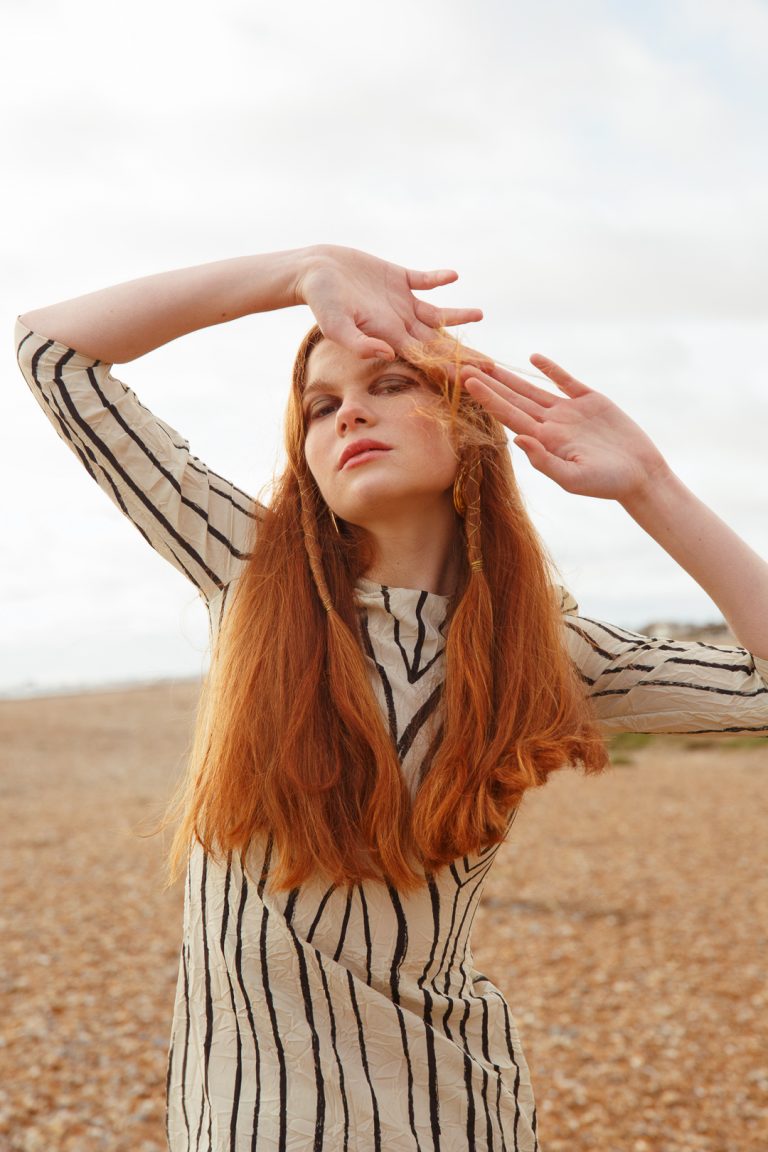Beautiful model wearing white & black stripe dress in a winter fashion shoot by Brighton seafront.