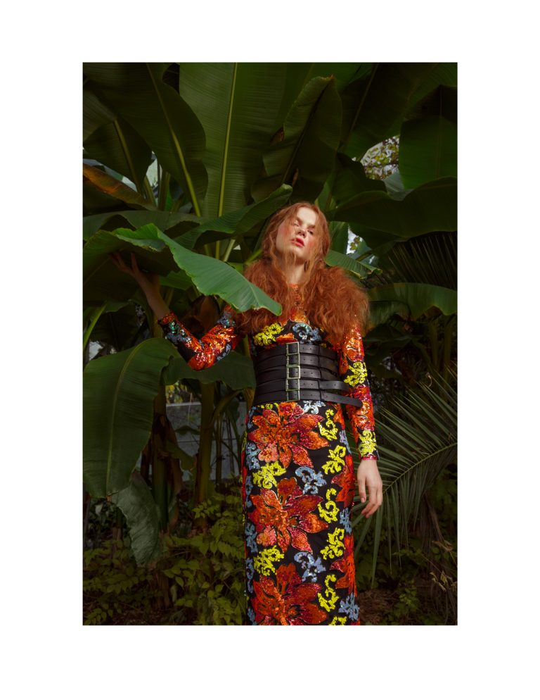 Model wearing a colourful dress, standing in a green house. Fashion photoshoot in Brighton.